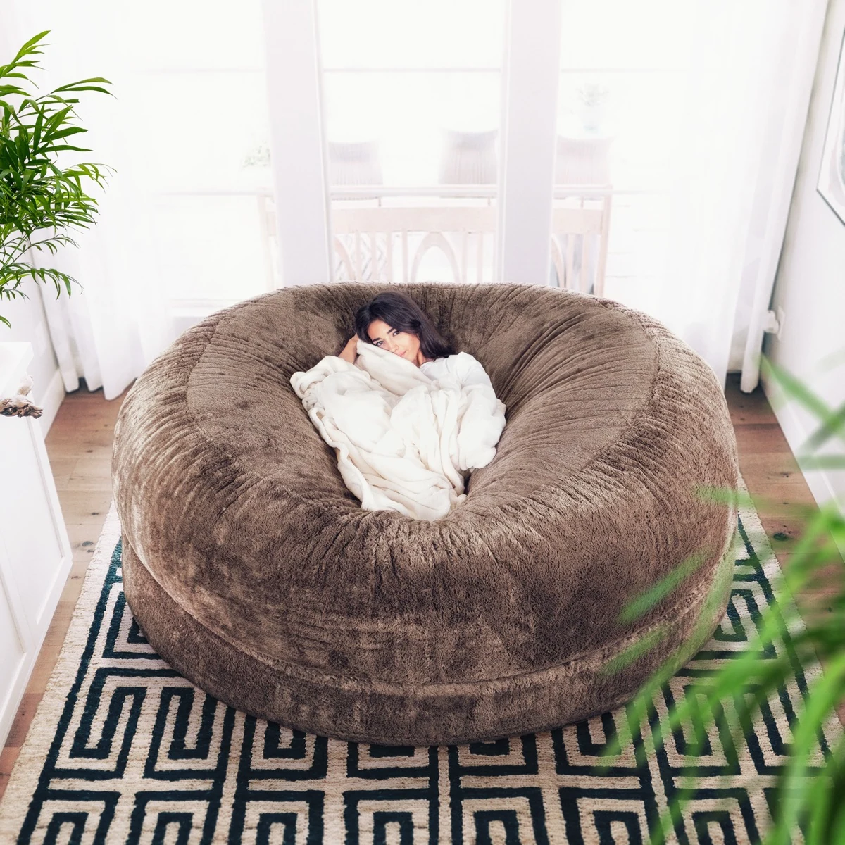 A person reclining on a brown Cosac beanbag, labeled 7ft in the manufacturer’s gallery, with the full chair visible